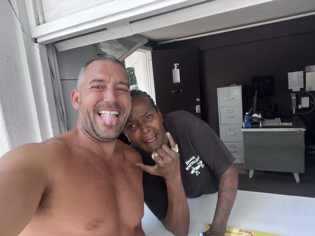 posing with Vicki from Honolulu Discount Cars, who throws a shaka and leans in with a playful expression.